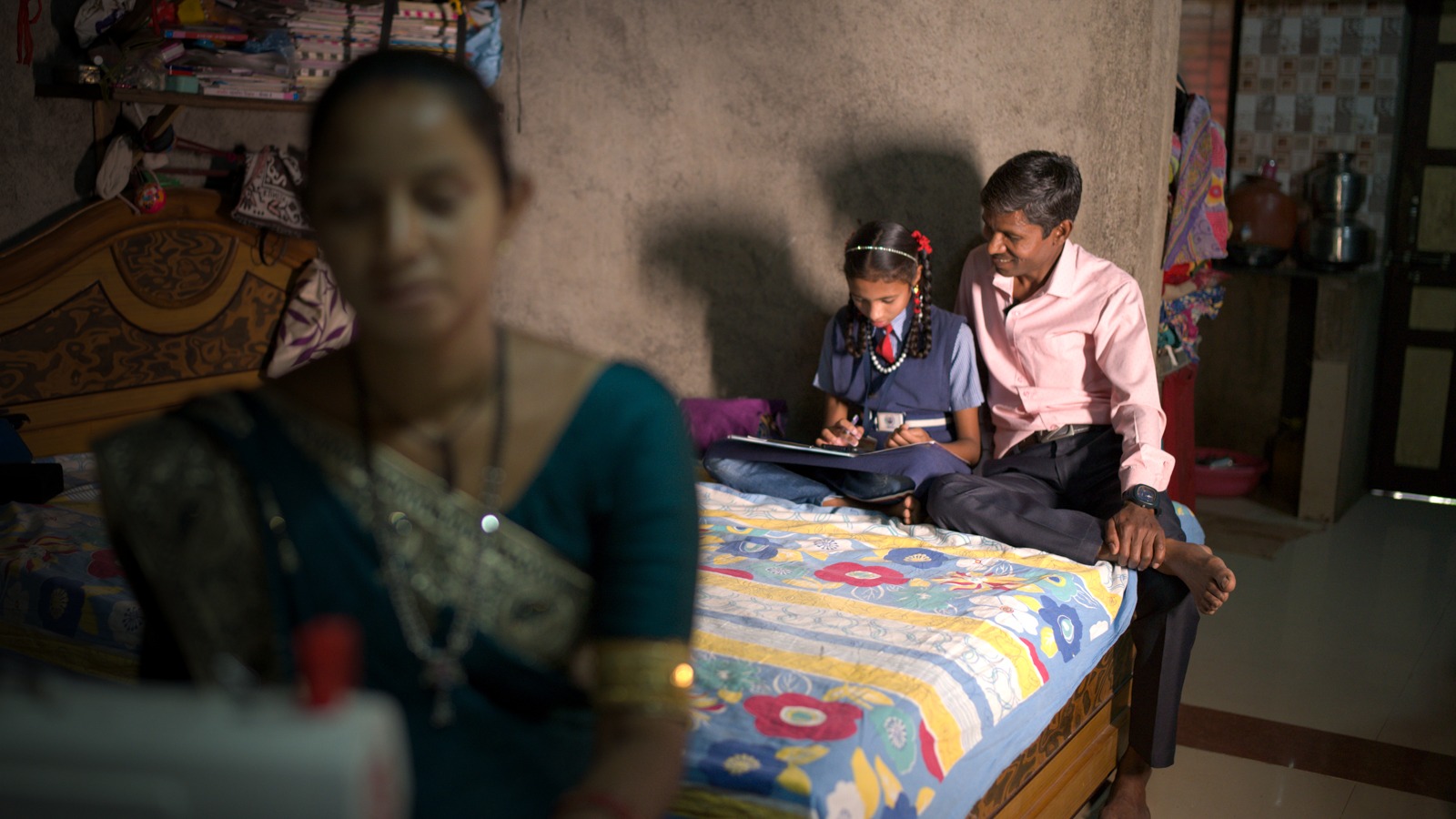An Indian father works on school work with his daughter in their home.