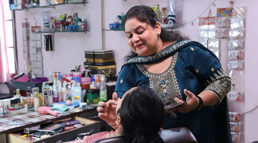 A woman works on another's woman's make-up in her salon.