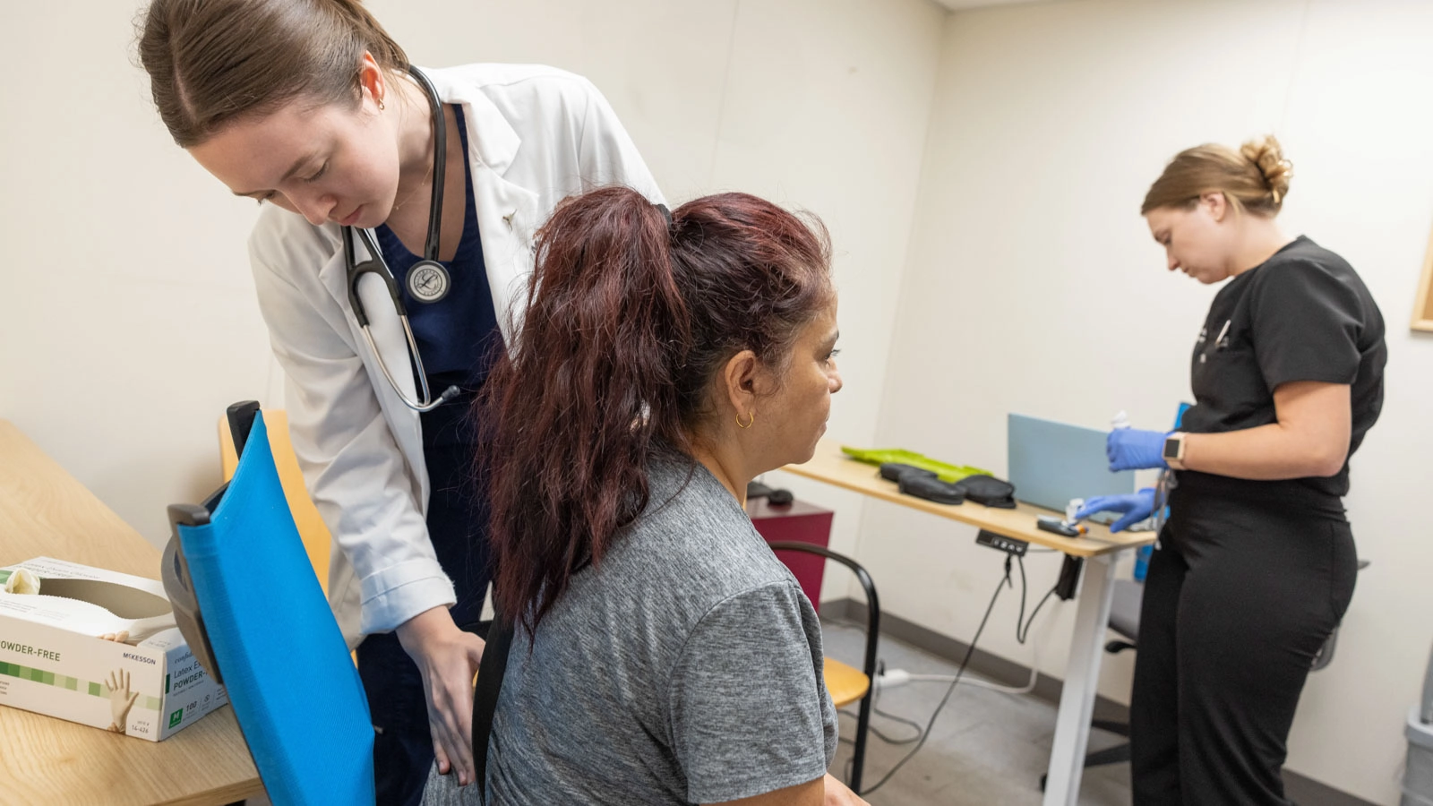 Two medical students record patient vitals during a clinical visit.
