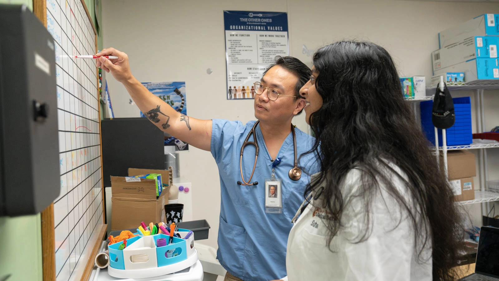 A physician coaches a medical student using a white board at the C.D. Doyle Clinic.