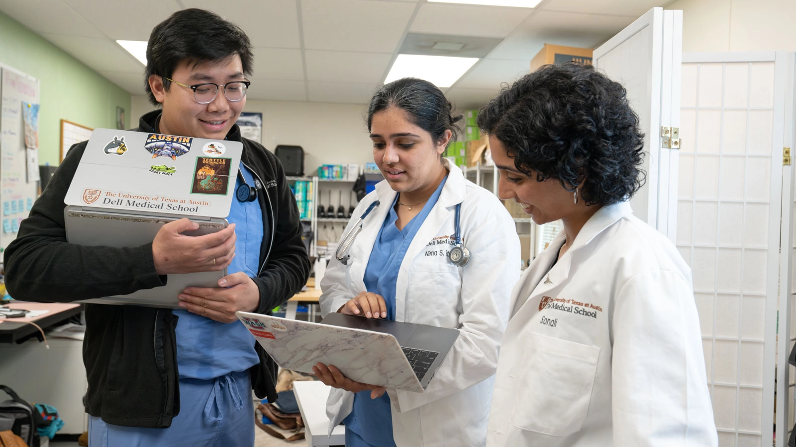 Sonali and two of her medical student peers collaborate in the clinic around their laptops.