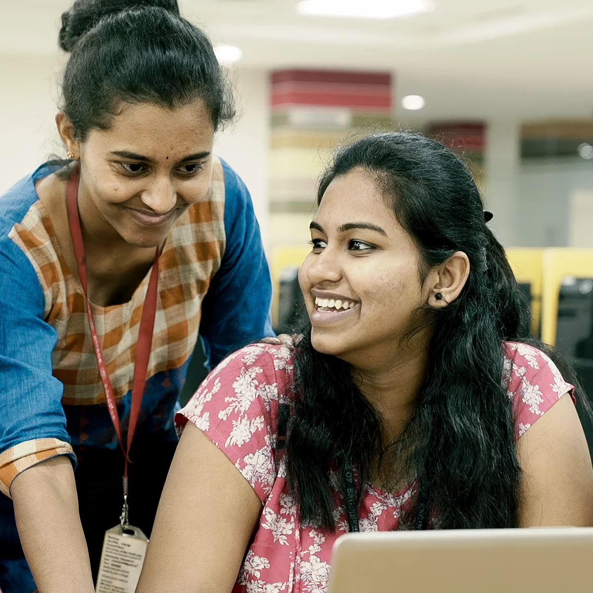 Smiling students work on a laptop.