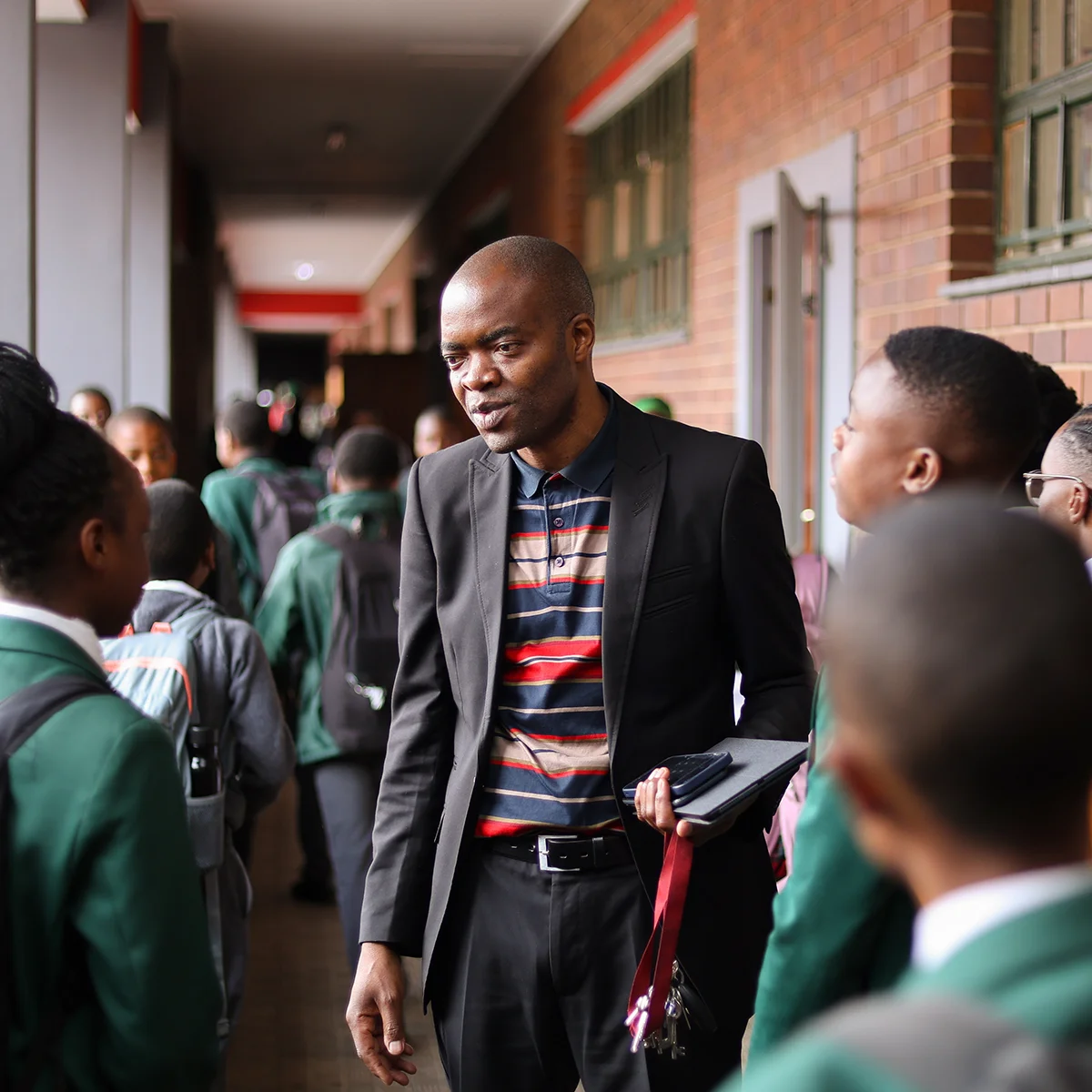 A teacher talks with students in a school hallway.