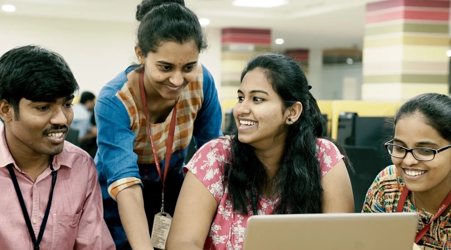 Smiling students work on a laptop.